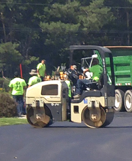 A roller compacting and smoothing a parking lot